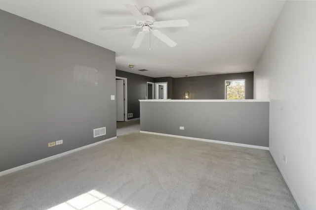 an empty room with windows and fan