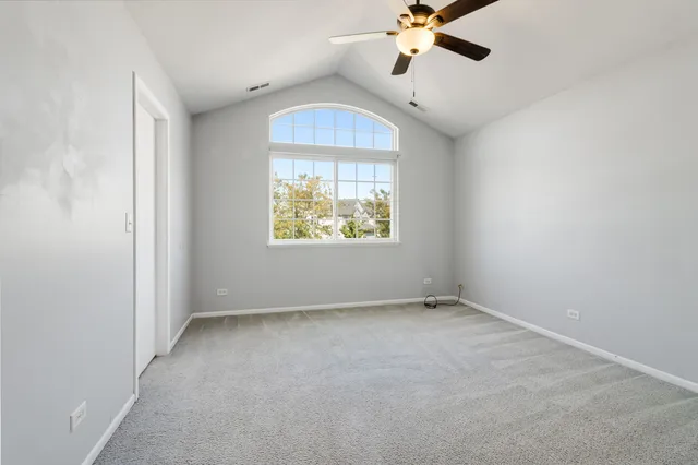 an empty room with ceiling fan and window