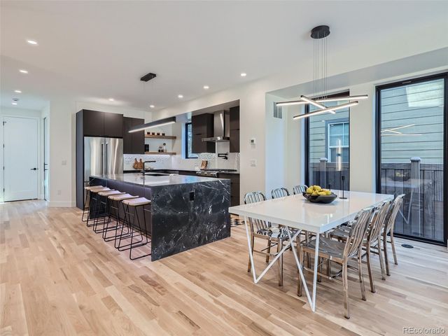 a kitchen with stainless steel appliances kitchen island granite countertop a table chairs sink and cabinets
