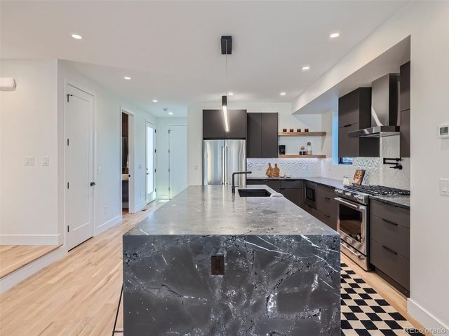 a large kitchen with stainless steel appliances granite countertop a large counter top a stove a sink and a refrigerator