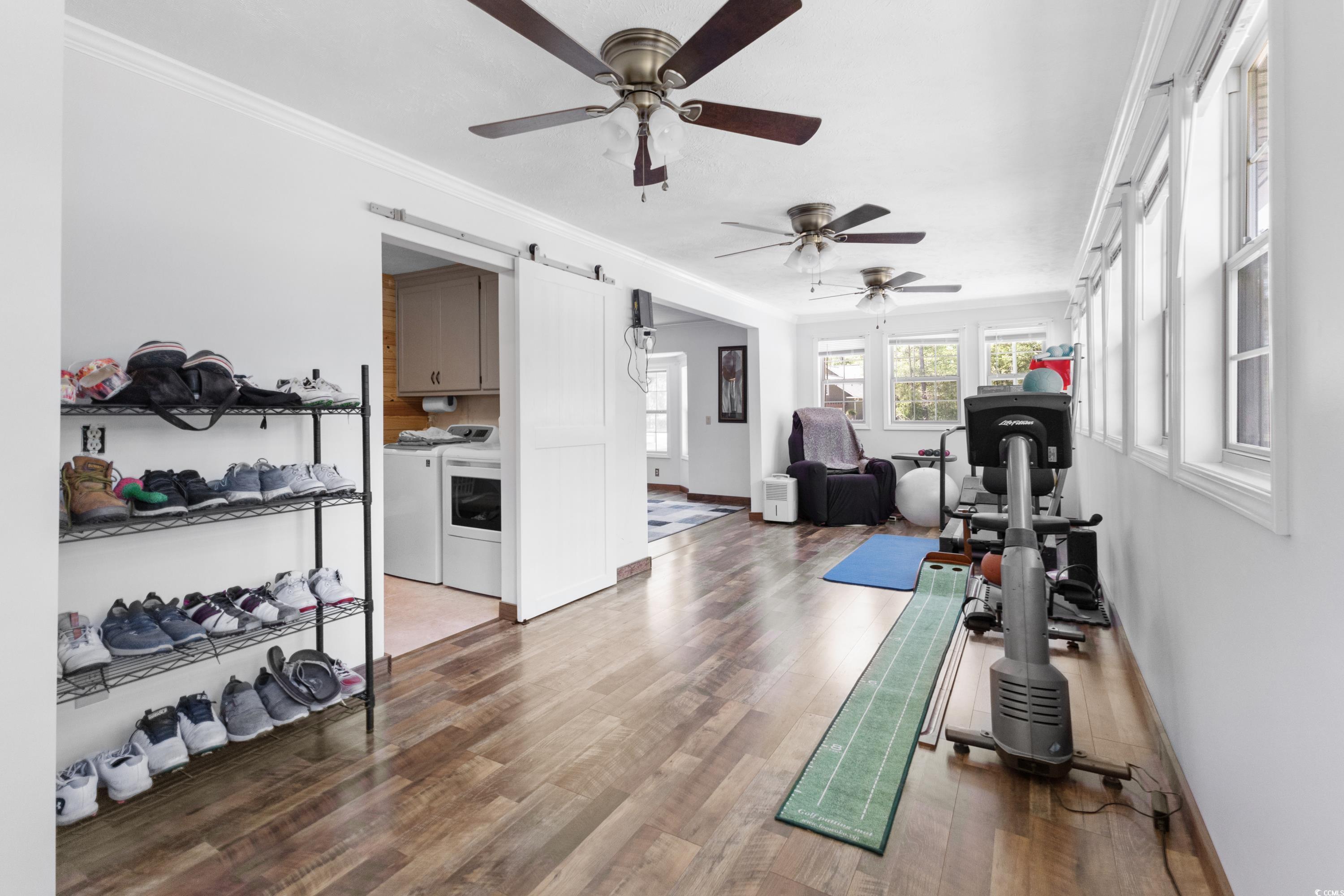1869 Meadowood Lane Longs, SC 29568 - Photo 15 of 37 Exercise area with a barn door, a ceiling fan, wood finished floors, separate washer and dryer, and ornamental molding