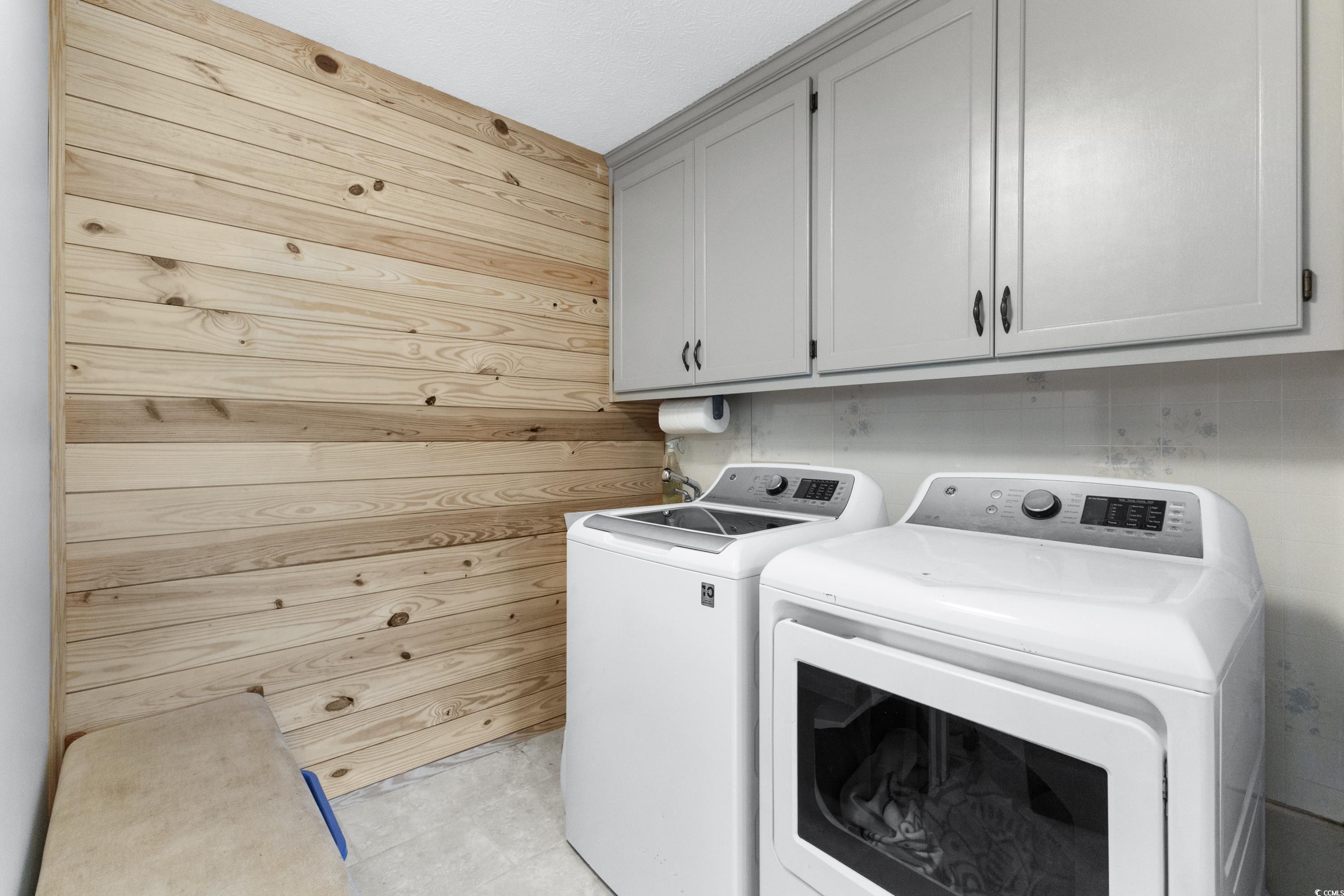 1869 Meadowood Lane Longs, SC 29568 - Photo 22 of 37 Clothes washing area with washing machine and clothes dryer, cabinet space, and wooden walls