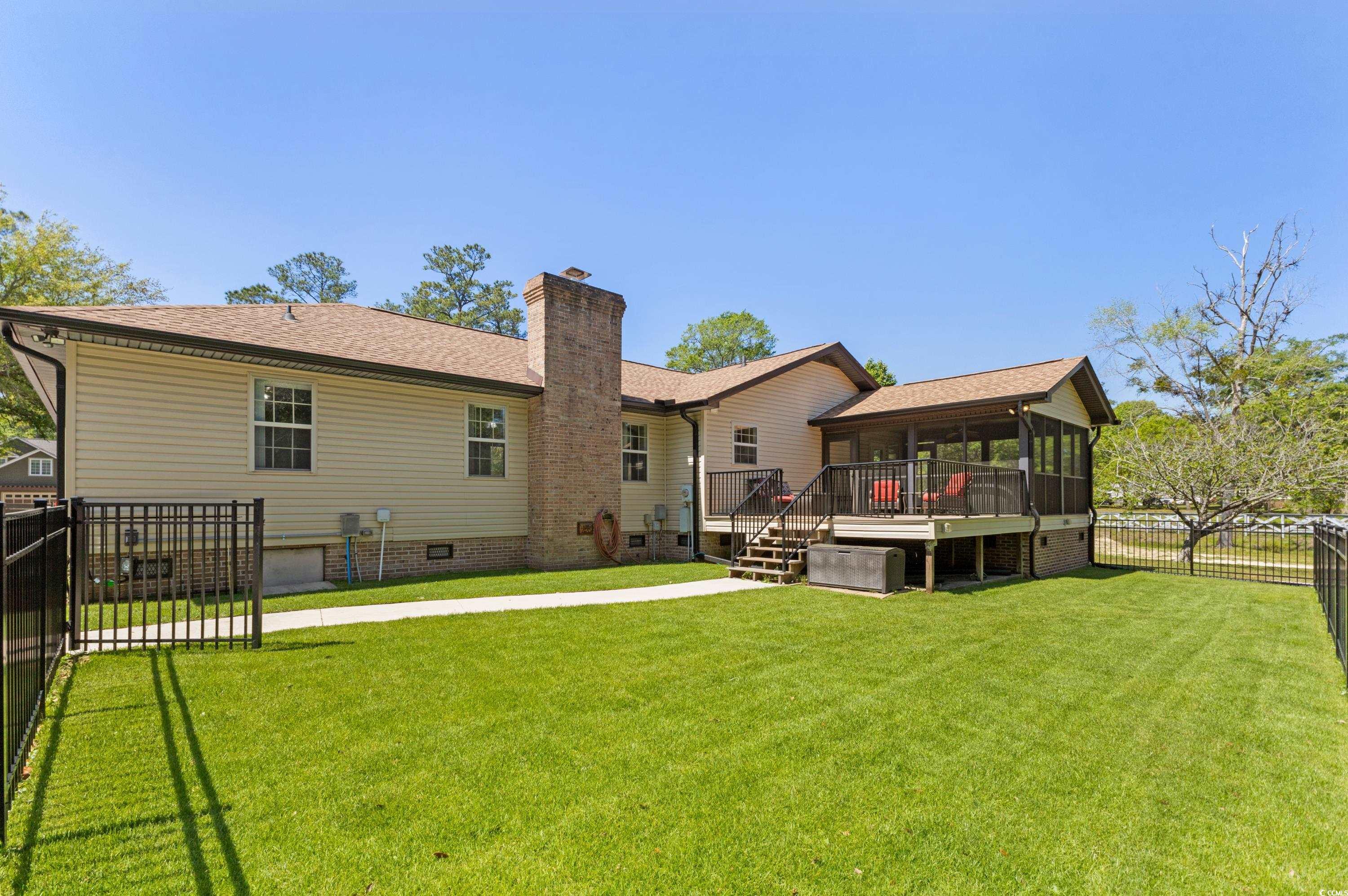 1869 Meadowood Lane Longs, SC 29568 - Photo 27 of 37 Rear view of house with a chimney, a deck, a yard, and a fenced backyard