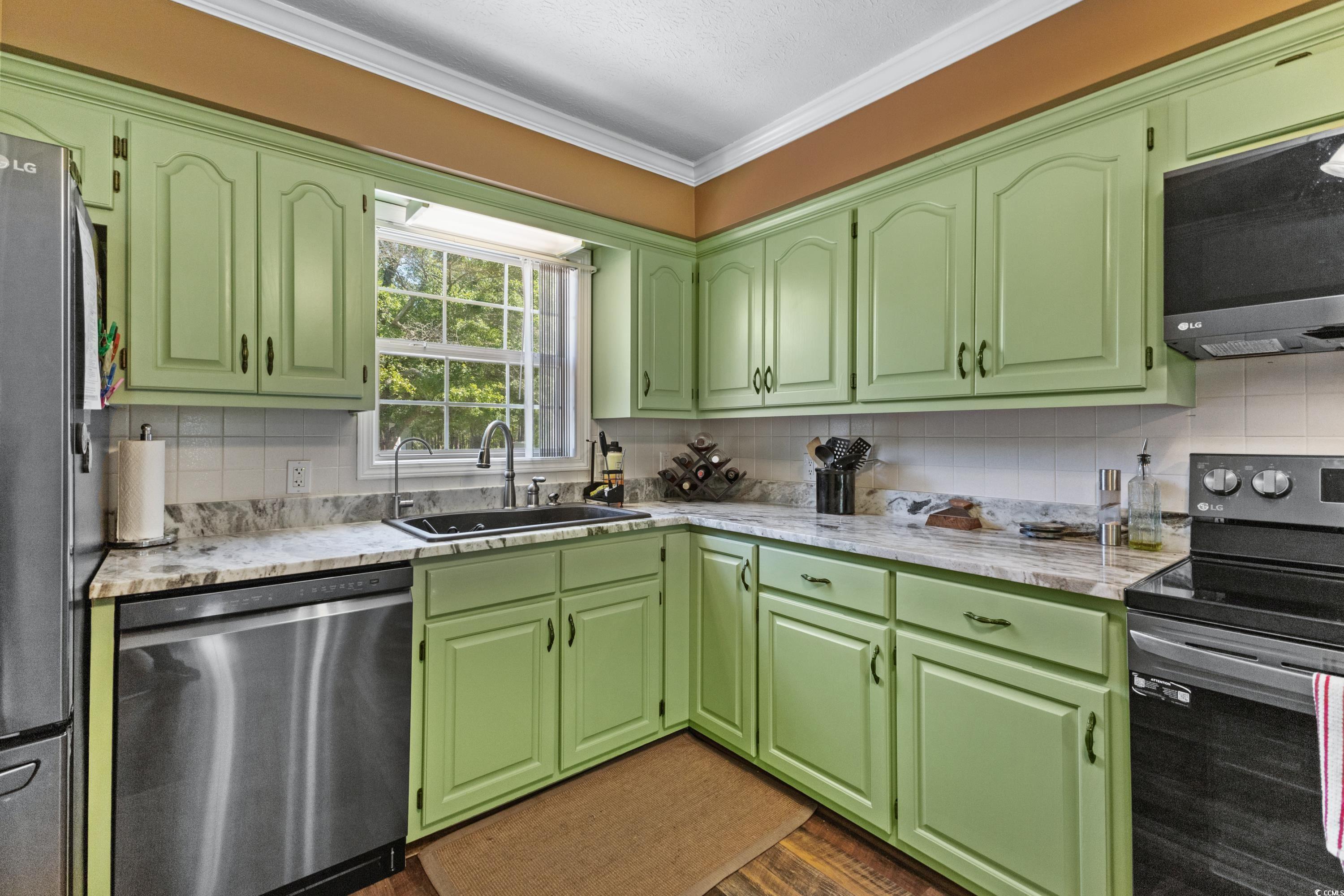 1869 Meadowood Lane Longs, SC 29568 - Photo 8 of 37 Kitchen with stainless steel appliances, a sink, backsplash, light countertops, and ornamental molding