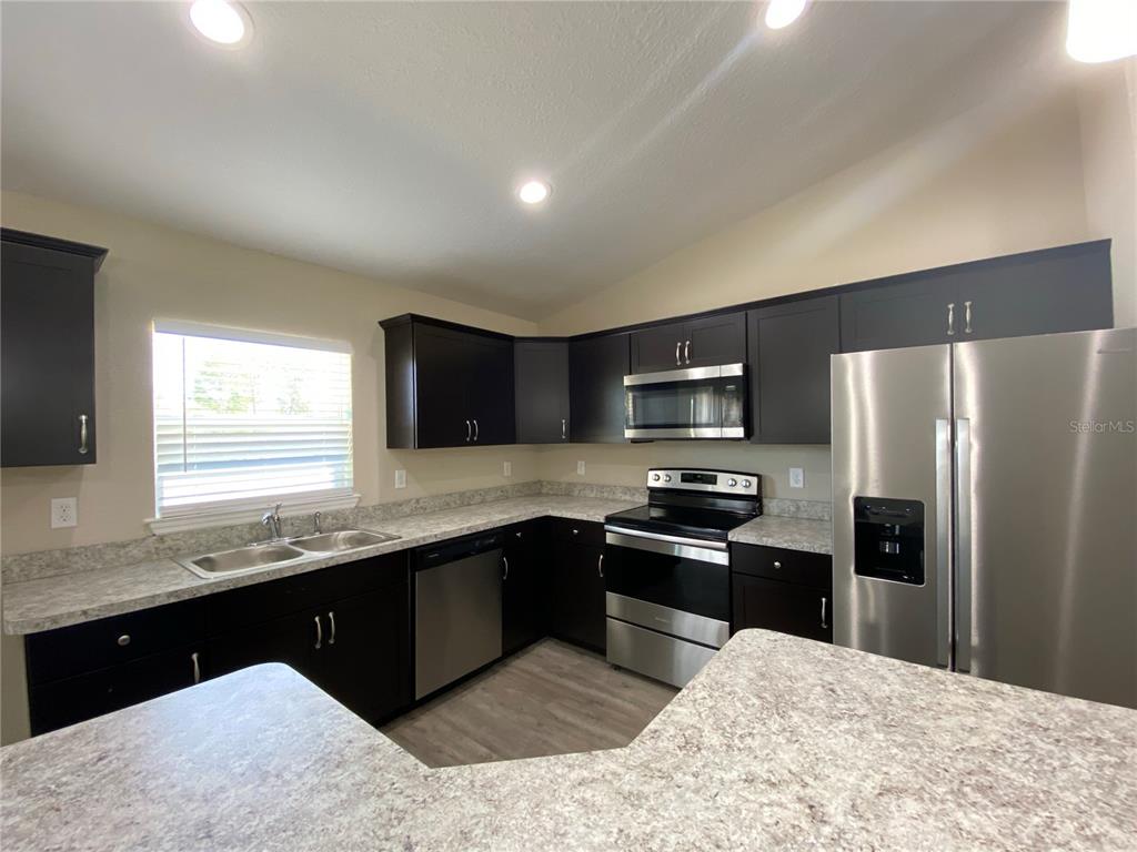 16767 Southwest 21st Terrace Road Ocala, FL 34473 - Photo 7 of 30 a kitchen with stainless steel appliances granite countertop a sink stove and refrigerator