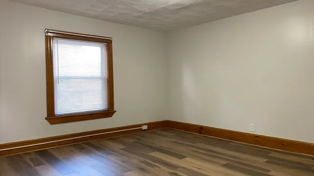 a view of an empty room and wooden floor and a window