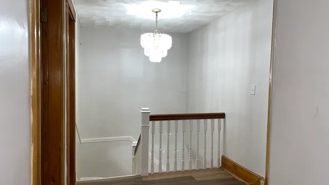 a view of a room with a hanging light and wooden floor