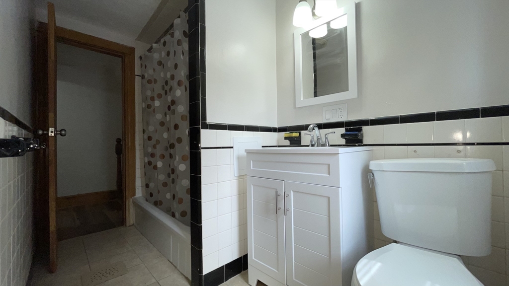 13 Whitman Street, Unit B Boston, MA 02124 - Photo 22 of 25 a bathroom with a toilet sink vanity and mirror