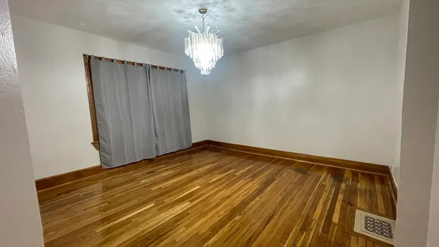 a view of a room with wooden floor and chandelier