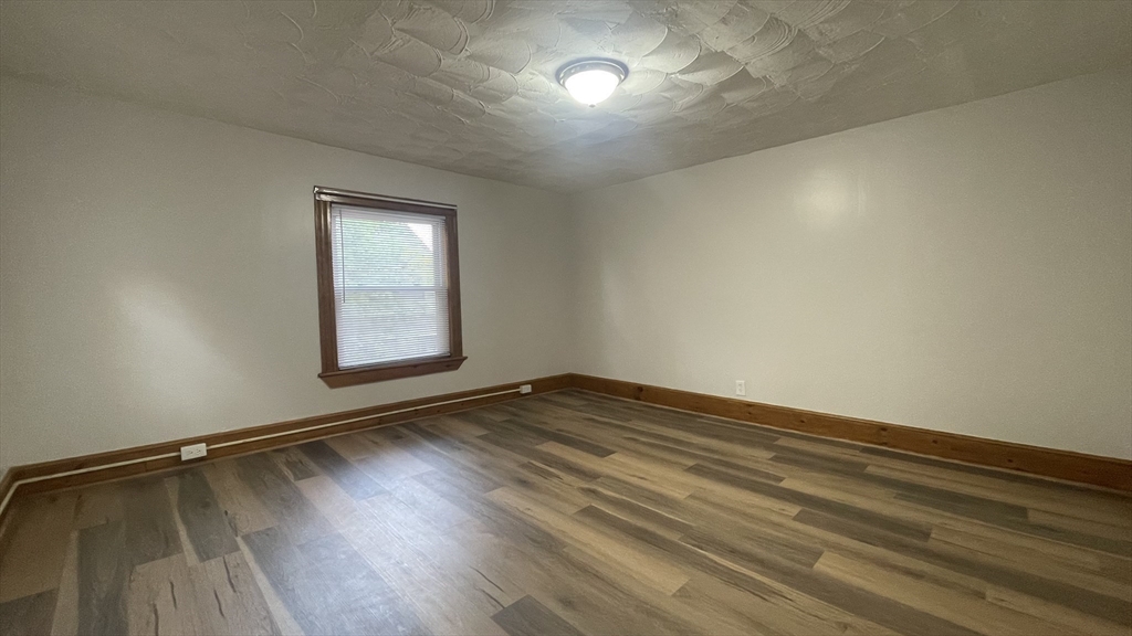 13 Whitman Street, Unit B Boston, MA 02124 - Photo 10 of 25 an empty room with wooden floor and windows