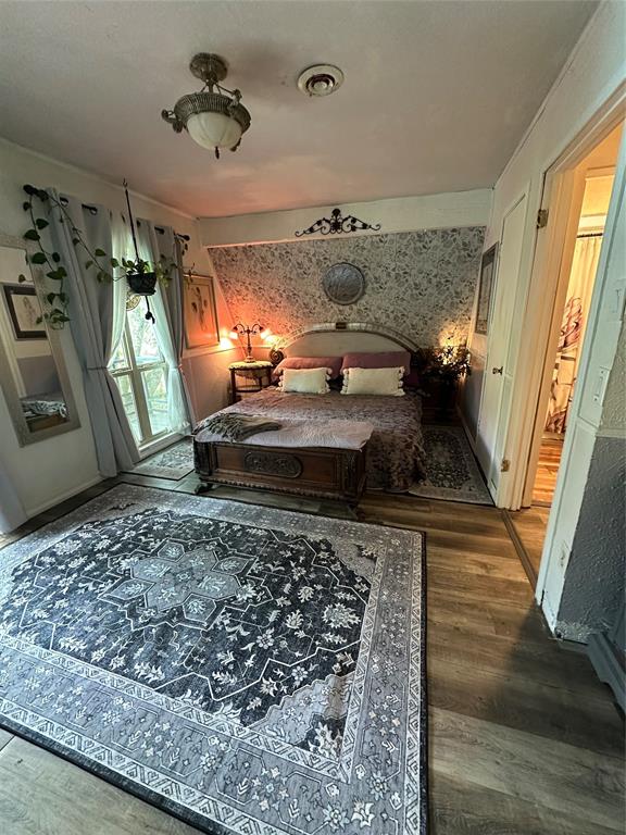 355 Spring Valley Street Gun Barrel City, TX 75156 - Photo 9 of 27 Spacious room featuring wood-finish flooring, an ornate ceiling light fixture, and a decorative wall panel above the bed