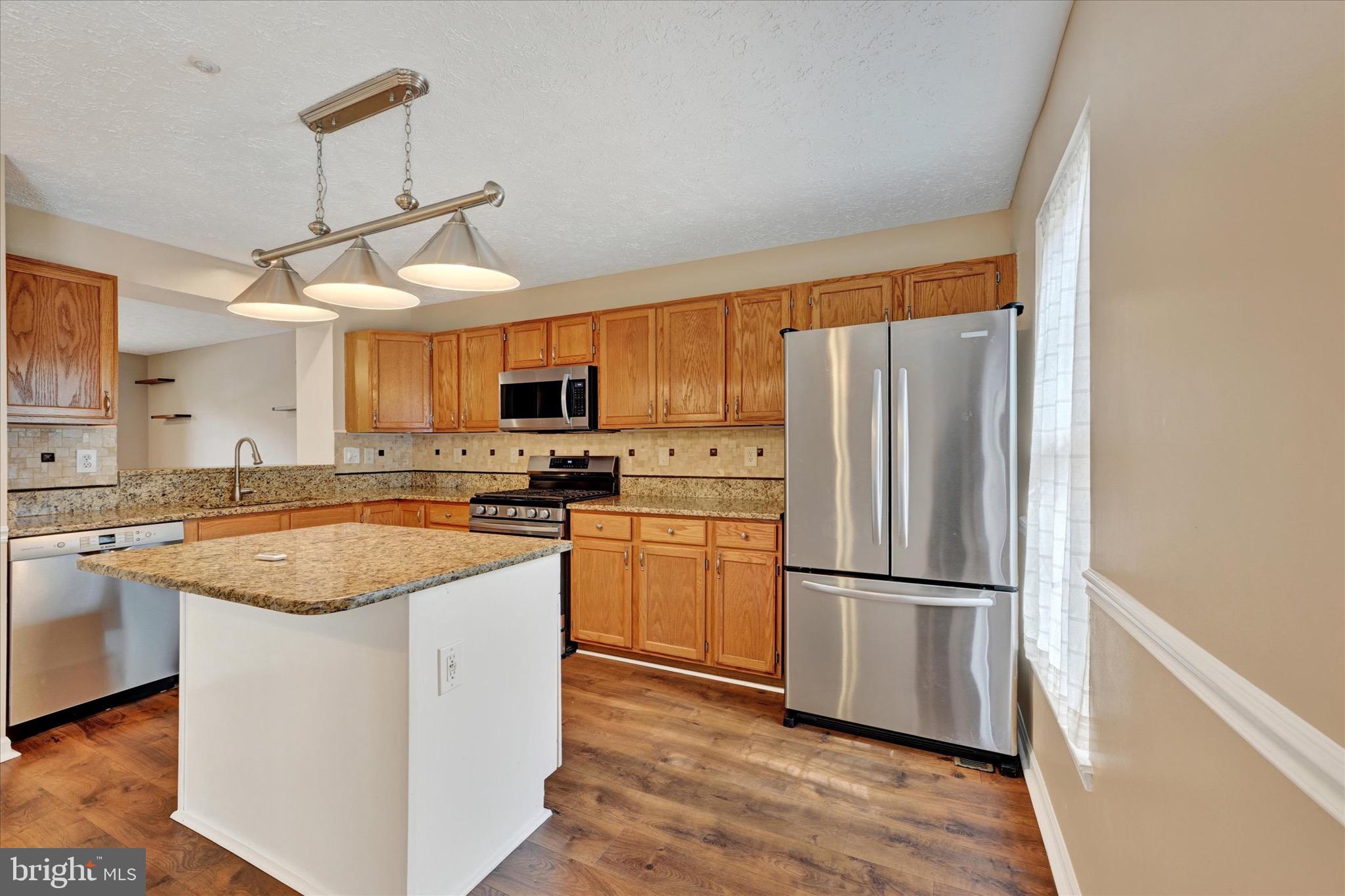 6119 Starburn Path Columbia, MD 21045 - Photo 9 of 28 a kitchen with stainless steel appliances granite countertop a refrigerator a stove a sink and a microwave