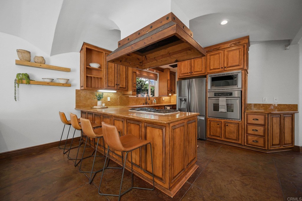 3209 James Drive Carlsbad, CA 92008 - Photo 17 of 65 a kitchen with stainless steel appliances granite countertop a kitchen island a stove a sink a dining table and chairs with wooden floor