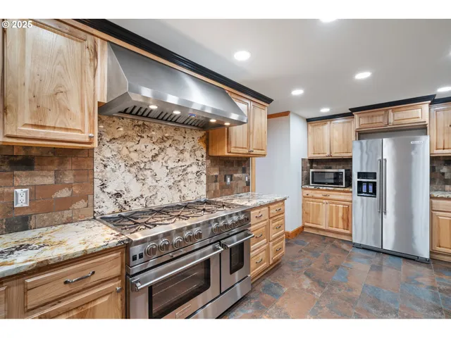 a kitchen with stainless steel appliances granite countertop a stove a sink and a refrigerator with wooden floor