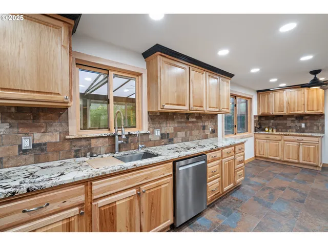 a kitchen with granite countertop a sink cabinets stainless steel appliances and a counter space