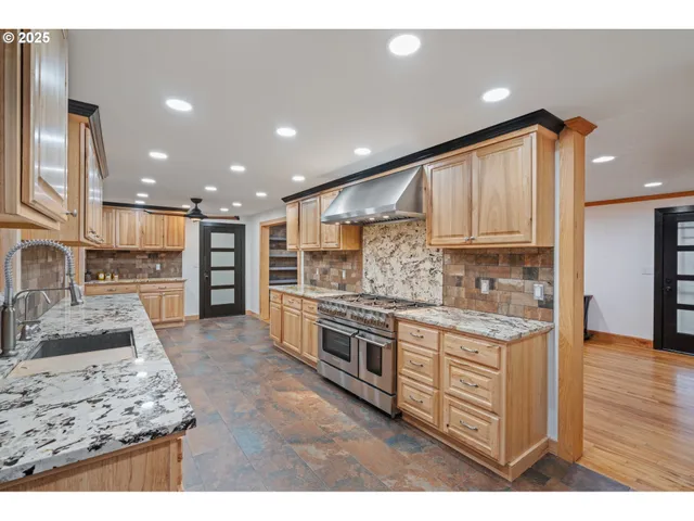 a kitchen with stainless steel appliances granite countertop a stove top oven a sink and a refrigerator