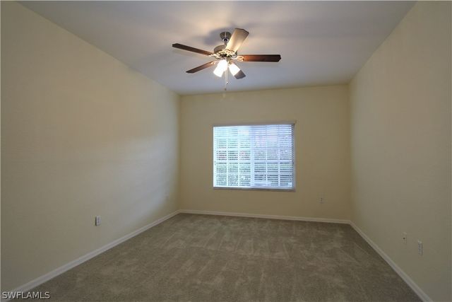 an empty room with a ceiling fan and window