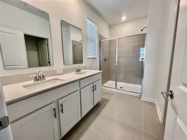 a bathroom with a double vanity sink mirror and shower