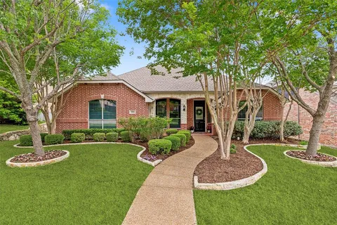 a front view of a house with a yard and tree
