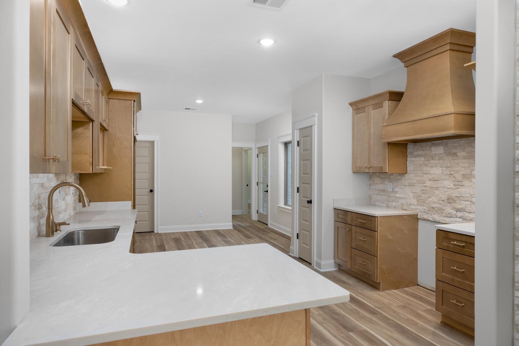 319 North Maple Street Covington, TN 38019 - Photo 12 of 32 Kitchen featuring decorative backsplash, light stone counters, light wood finished floors, a peninsula, and recessed lighting