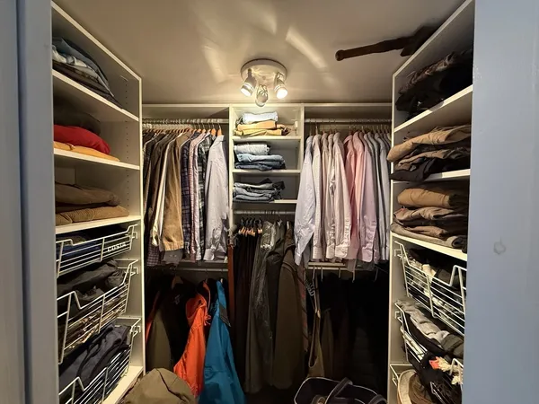 a view of walk in closet with clothes and shoes