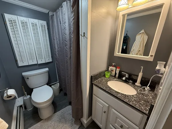 a bathroom with a granite countertop toilet a sink and a mirror