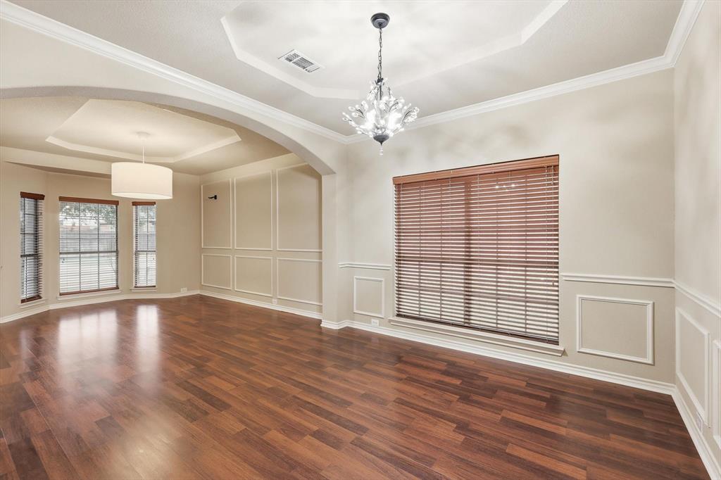 5038 West Fall Drive Midlothian, TX 76065 - Photo 13 of 40 Empty room featuring a raised ceiling, a decorative wall, arched walkways, dark wood-type flooring, and ornamental molding
