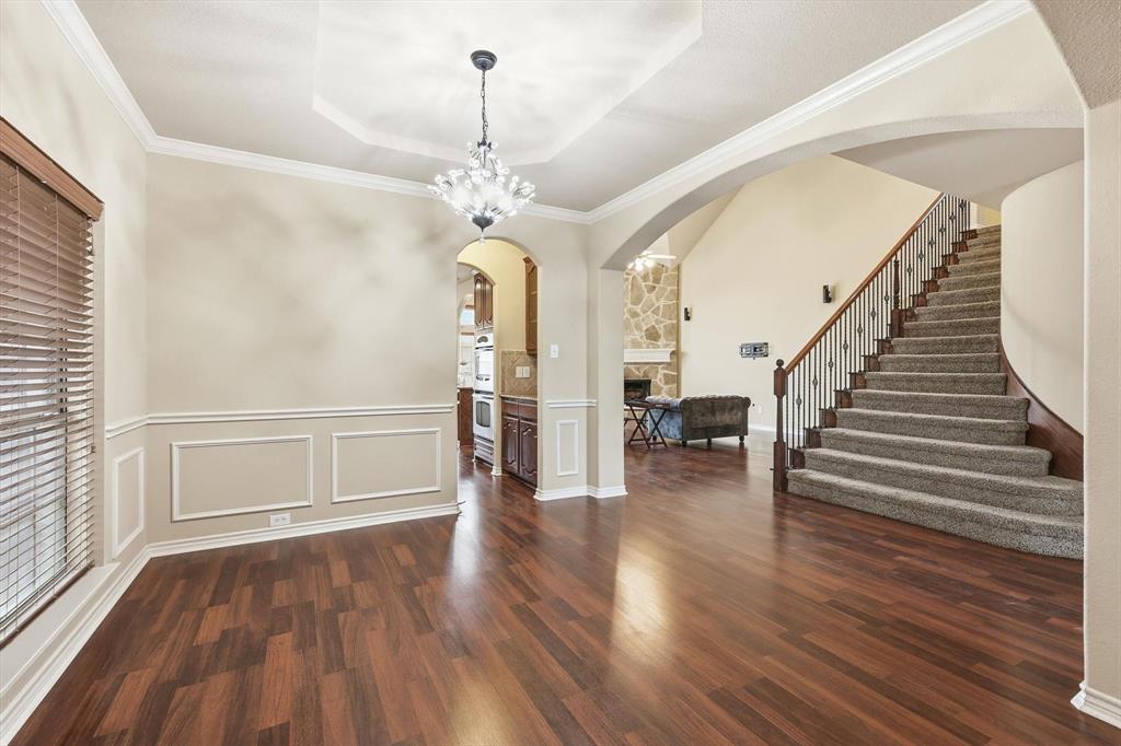5038 West Fall Drive Midlothian, TX 76065 - Photo 14 of 40 Unfurnished dining area with hanging lights, arched walkways, crown molding, dark wood finished floors, and a stone fireplace