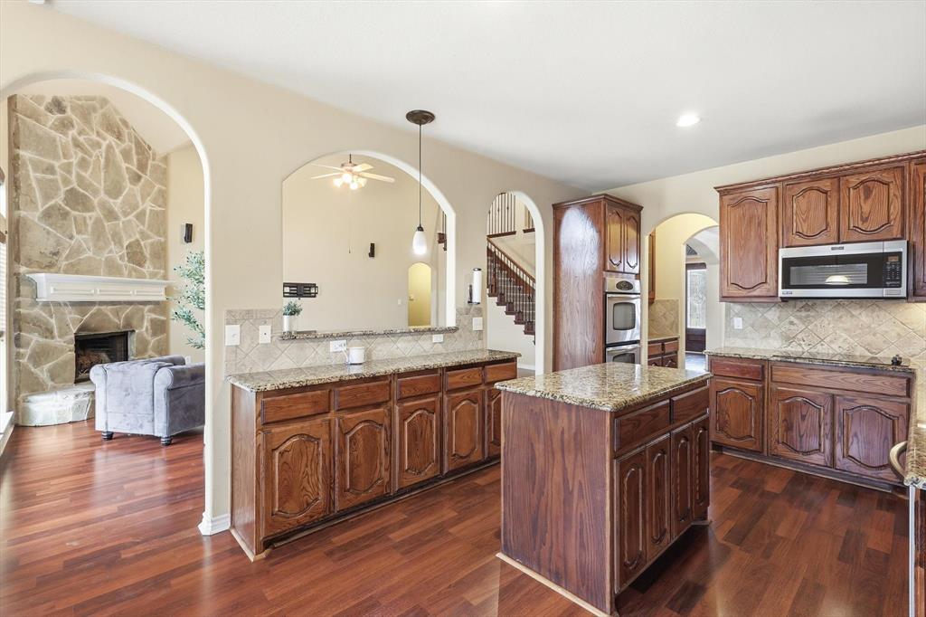 5038 West Fall Drive Midlothian, TX 76065 - Photo 40 of 40 Kitchen featuring light stone countertops, arched walkways, stainless steel appliances, open floor plan, and pendant lighting