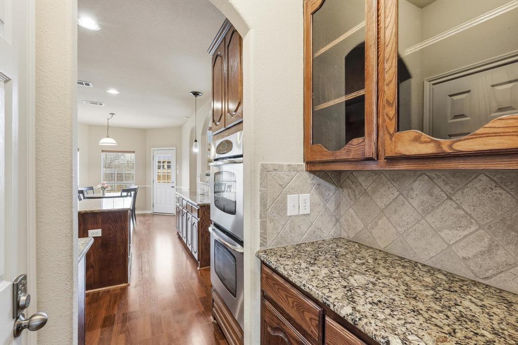 5038 West Fall Drive Midlothian, TX 76065 - Photo 19 of 40 Kitchen featuring light stone counters, pendant lighting, double oven, dark wood finished floors, and glass fronted cabinets
