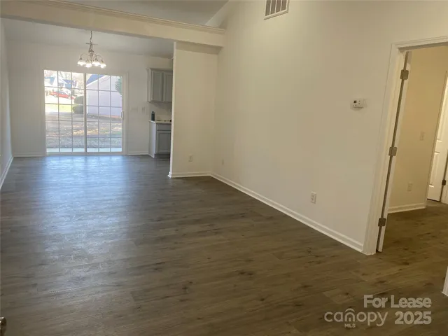 an empty room with wooden floor and chandelier