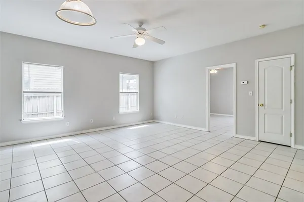 an empty room with windows and fan