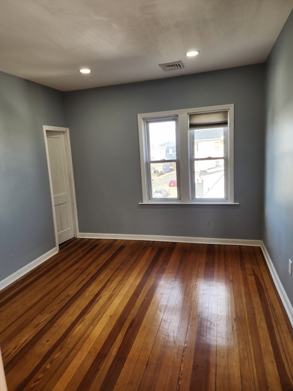 146 Middlesex Street, Unit 3 Fall River, MA 02723 - Photo 6 of 9 an empty room with wooden floor and windows