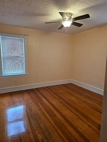 a view of room with hardwood floor and a ceiling fan