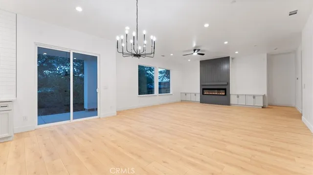 a view of an empty room with a chandelier and a kitchen