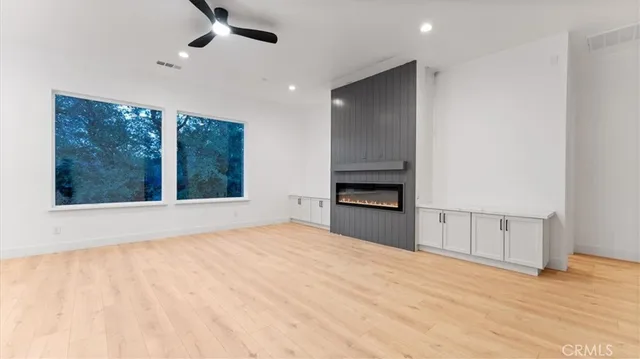 a view of an empty room with a window and kitchen view