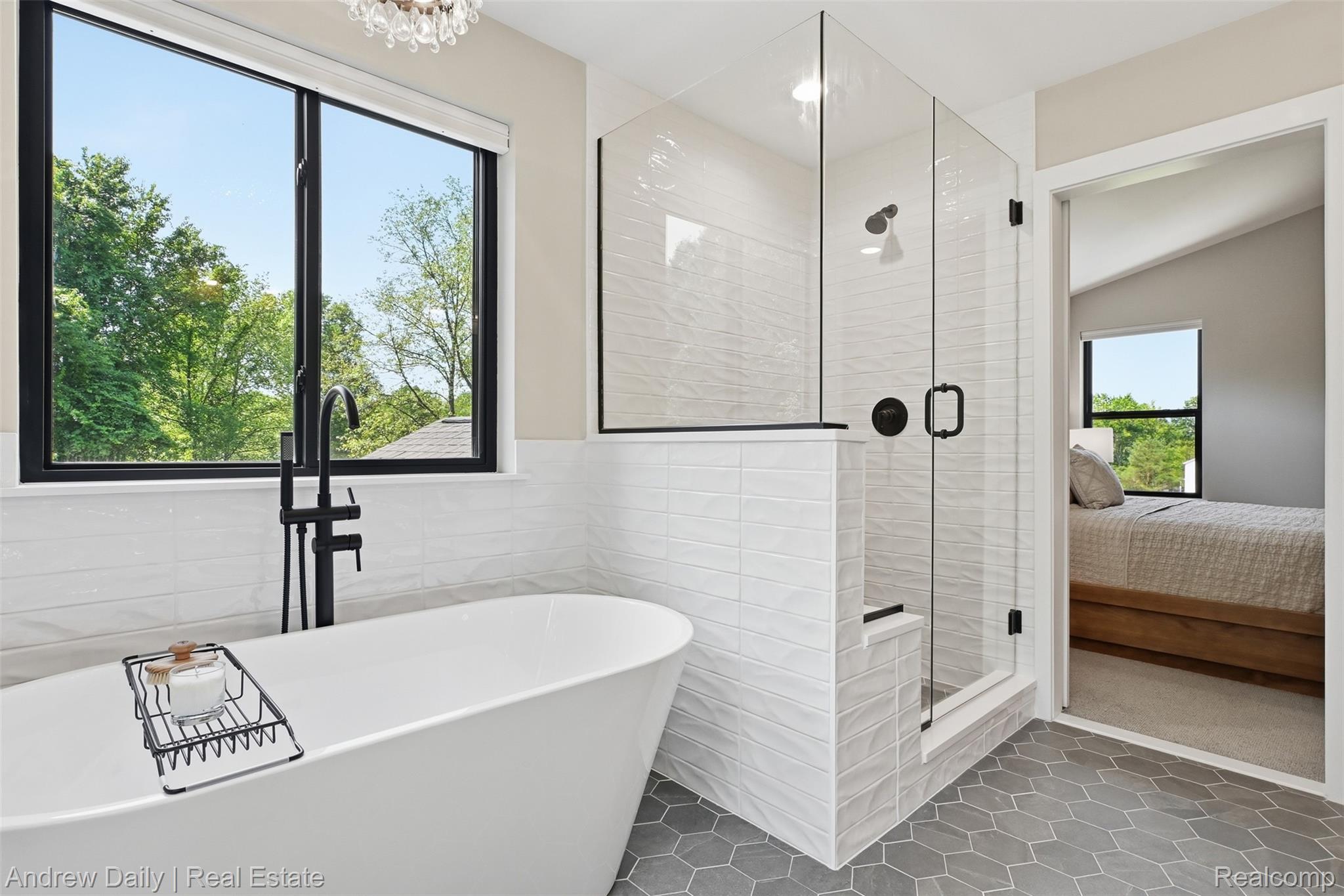 4661 Spears Road Pinckney, MI 48169 - Photo 36 of 56 Freestanding soaking tub with a floor-mounted matte black faucet, walk-in shower featuring a glass enclosure and built-in bench, hexagonal floor tiles, and a large window with black trim