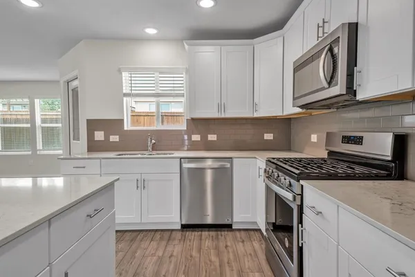 a kitchen with stainless steel appliances granite countertop a stove a sink and a microwave
