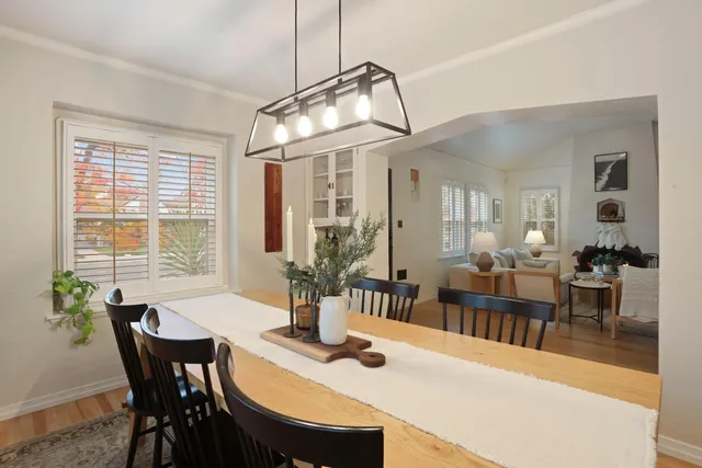a dining room with wooden floor a chandelier a wooden table and chairs