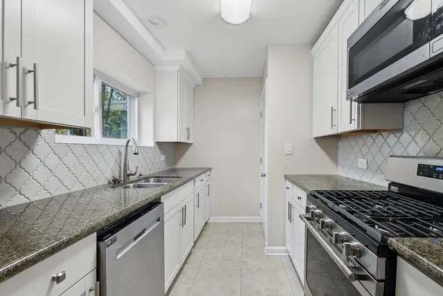 a kitchen with granite countertop a sink stove and cabinets