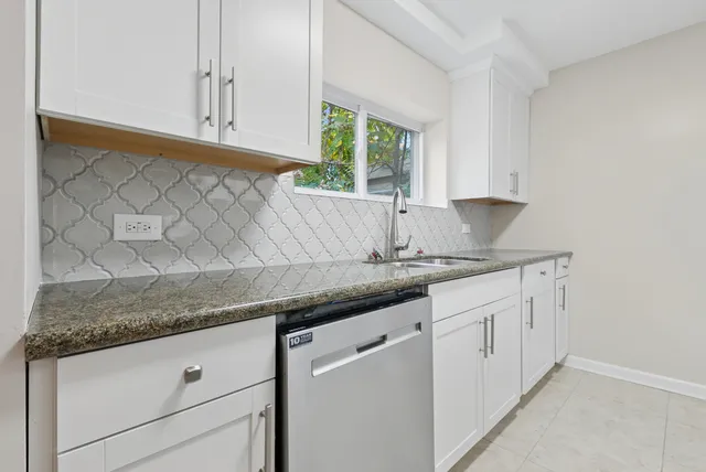 a kitchen with granite countertop white cabinets and a sink