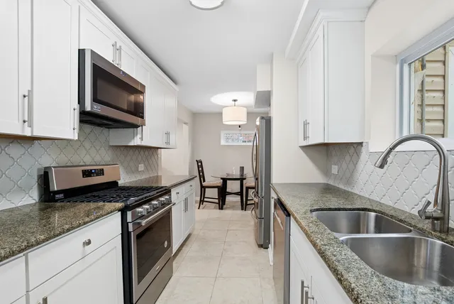 a kitchen with granite countertop a sink a stove and cabinets