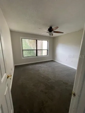an empty room with windows and a ceiling fan