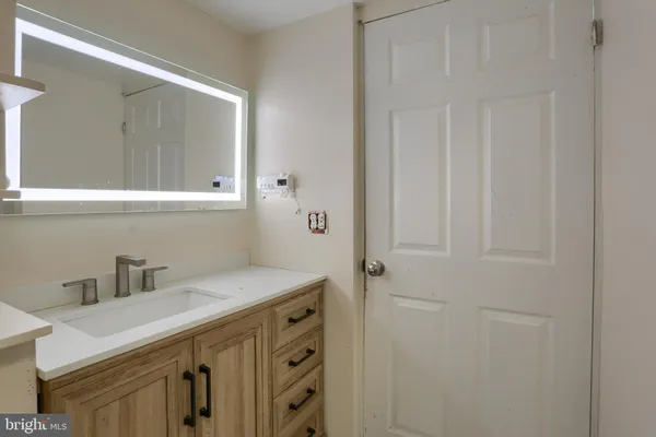 a view of an empty room with wooden floor and a bathroom