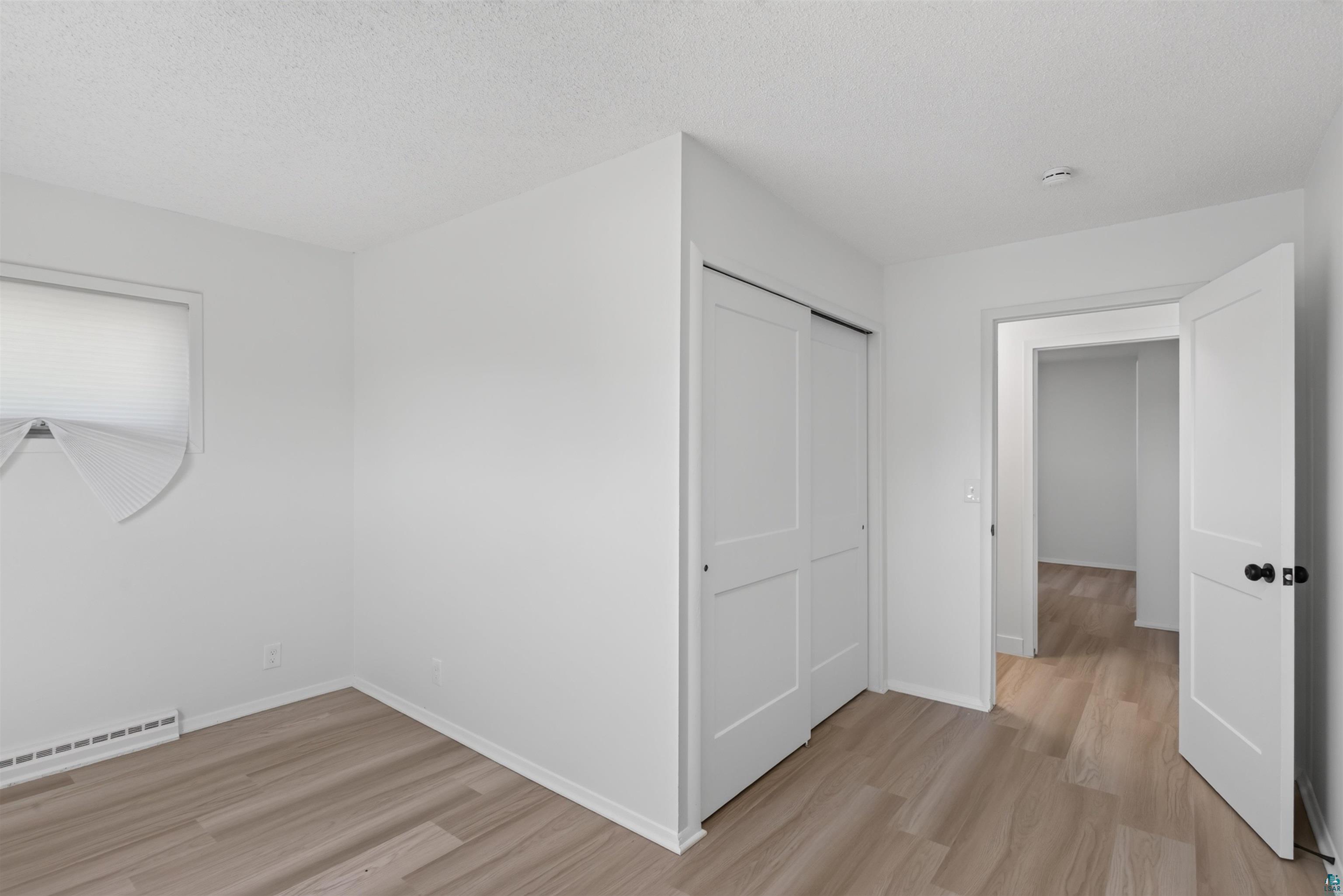 5868 Rice Lake Road Duluth, MN 55803 - Photo 24 of 39 Bright room featuring wood-finish flooring, white walls, and a closet with bifold doors