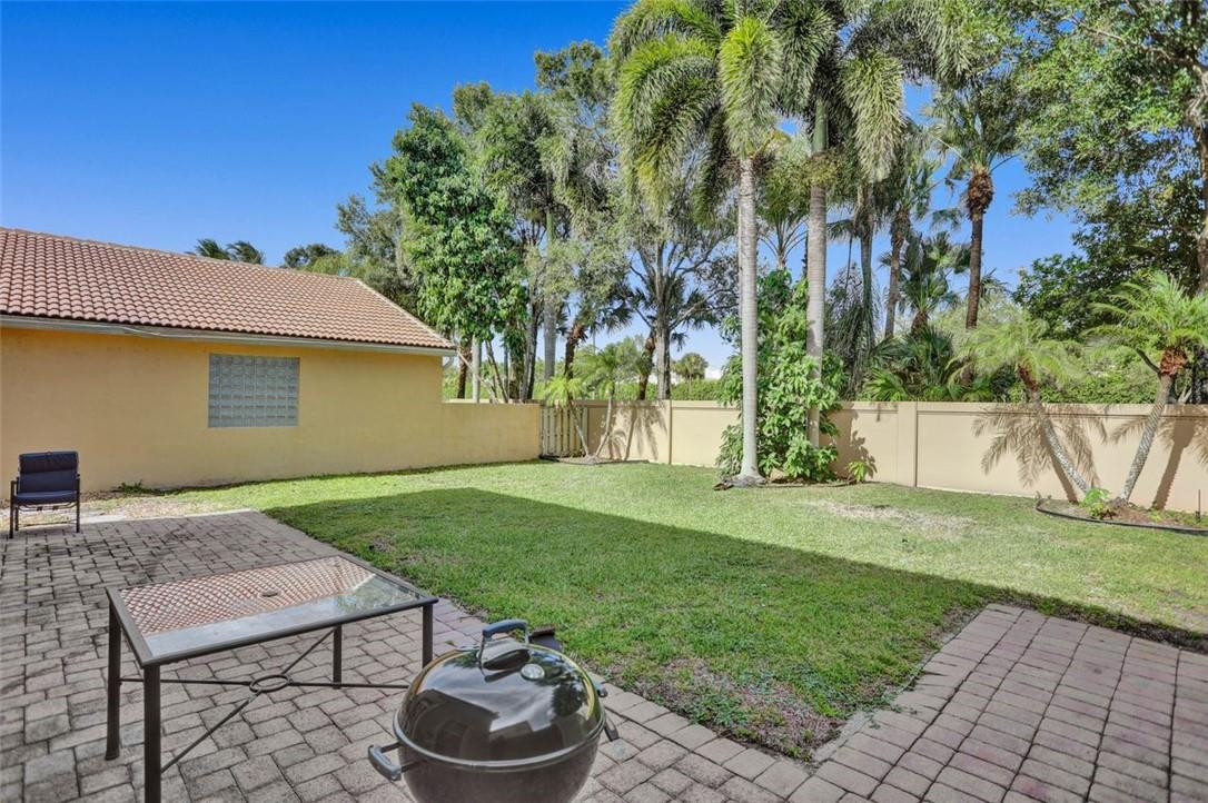 5257 Sancerre Circle Lake Worth, FL 33463 - Photo 8 of 46 a backyard of a house with barbeque oven table and chairs