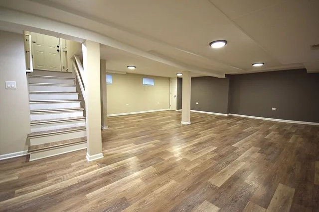 a view of an empty room with wooden floor and stairs