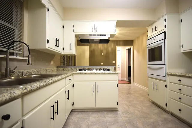 a kitchen with granite countertop a sink a stove and cabinets