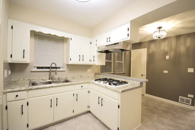 a kitchen with granite countertop a sink cabinets and stainless steel appliances
