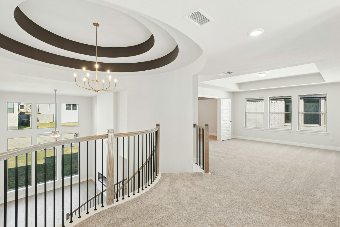 1528 Rodeo Ridge Drive Georgetown, TX 78628 - Photo 14 of 28 Hallway with a raised ceiling, an upstairs landing, carpet, and a chandelier
